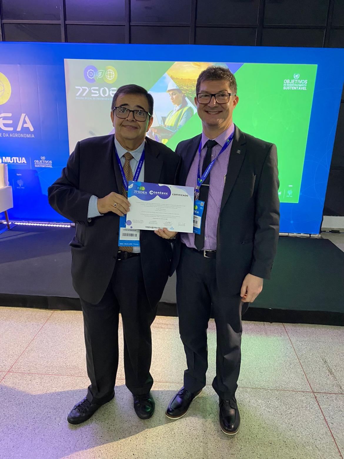 O conselheiro federal eng. eletric. Jorge Bitencourt recebe o certificado de participação do mediador da mesa, conselheiro federal eng. eletric. Evânio Nicoleit